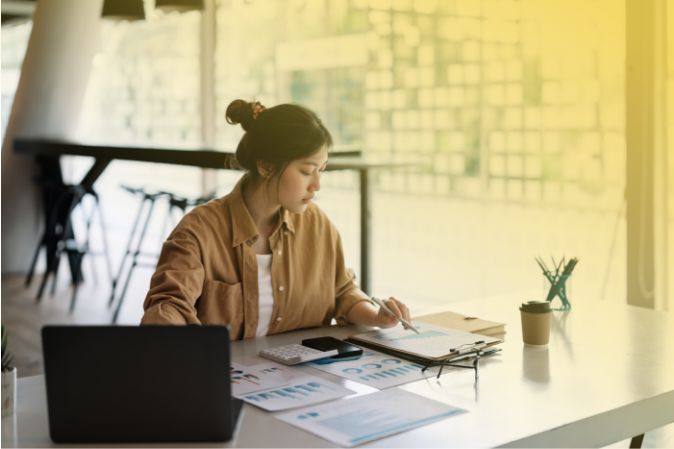 Mujer estudiando varias hojas de datos en papel en un escritorio